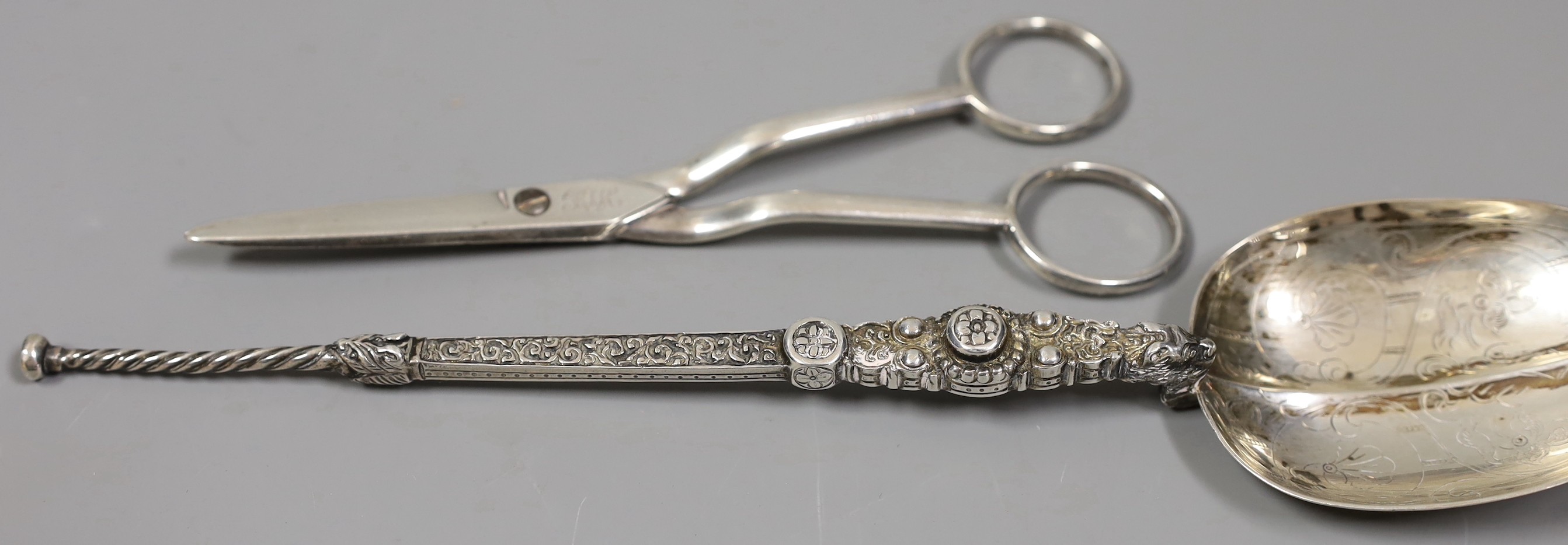 A pair of George III silver grape scissors, by Eley & Fearn, London, 1818 and a George V silver replica of the anointing spoon, Goldsmiths & Silversmiths Co Ltd, London 1910, 166 grams.